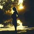 Pregnant woman silhouette standing in the park among the trees, a figure in the opposite light