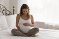 Pregnant woman sit on bed touch belly feeling unconditional love Royalty Free Stock Photo