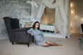 Pregnant woman sit near the armchair. Beautiful woman waiting for a baby. Elegant pregnant model at home Royalty Free Stock Photo