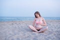 Pregnant woman sits on the beach and enjoys. Soft evening light, deserted beach Royalty Free Stock Photo