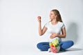 A pregnant woman sits on a white background and wants to eat a tomato Royalty Free Stock Photo