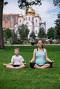 Pregnant woman sits in yoga posies and meditates with her son