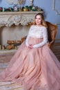 A pregnant woman sitting in a beautiful dress on the couch. the concept of motherhood