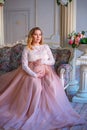 A pregnant woman sitting in a beautiful dress on the couch. the concept of motherhood