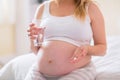 Pregnant woman sitting on bed and holding glass of water Royalty Free Stock Photo