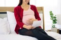 Pregnant woman sitting on bed and looking at her ultrasound image of her child in her belly Royalty Free Stock Photo