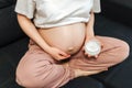 Pregnant Woman sitting on bed stroking apply cream on big belly at home Royalty Free Stock Photo