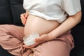 Pregnant Woman sitting on bed stroking apply cream on big belly at home Royalty Free Stock Photo