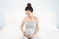 Pregnant woman sitting on the bed and touching her belly at home. Selective focus. Royalty Free Stock Photo