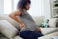 Pregnant woman sitting on the couch lower back pain and headache, strain on the spine during pregnancy. Lifestyle