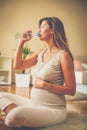 Pregnant woman sitting on floor and drinking water. Royalty Free Stock Photo