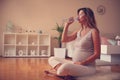 Pregnant woman sitting on floor and drinking water. Royalty Free Stock Photo