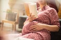 Pregnant woman sitting on floor at home and reading book Royalty Free Stock Photo