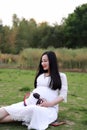 Pregnant woman sitting on grass lawn listen to music enjoy peaceful time in nature Asian Chinese antenatal training outdoor