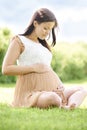 Pregnant Woman Sitting On Grass Outdoors Holding Bump Royalty Free Stock Photo