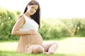 Pregnant Woman Sitting On Grass Outdoors Holding Bump Royalty Free Stock Photo