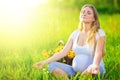 Pregnant woman sitting on green field Royalty Free Stock Photo