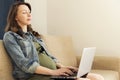 Pregnant woman sitting with laptop at home. Freelance working, p