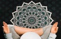 Pregnant woman sitting in lotus position on mandala yoga mat and meditating. Top view