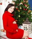 Pregnant woman sitting near the Christmas tree