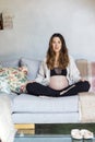 Pregnant woman sitting on a sofa and caressing her belly Royalty Free Stock Photo