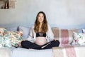 Pregnant woman sitting on a sofa and caressing her belly Royalty Free Stock Photo