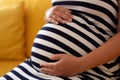 Pregnant woman sitting at sofa and caressing her belly Royalty Free Stock Photo