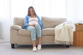 Pregnant woman sitting on sofa in casual comfortable clothes Royalty Free Stock Photo