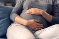 Pregnant woman sitting on the sofa and holding her belly Royalty Free Stock Photo