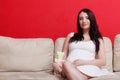 Pregnant woman sitting on sofa holding teddy bear Royalty Free Stock Photo