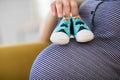 Close Up Of Pregnant Woman Sitting On Sofa At Home Holding Baby Shoes On Stomach Royalty Free Stock Photo