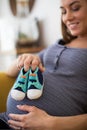 Pregnant Woman Sitting On Sofa At Home Holding Baby Shoes Royalty Free Stock Photo