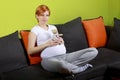 Pregnant woman sitting on sofa with teddy bear