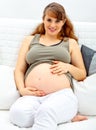 Pregnant woman sitting on sofa and touching belly Royalty Free Stock Photo