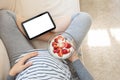 Pregnant woman sitting sofa using digital tablet while eating yogurt Royalty Free Stock Photo