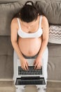 Pregnant Woman Sitting On Sofa Using Laptop Royalty Free Stock Photo