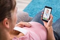 Pregnant Woman Sitting On Sofa Video Conferencing With Doctor