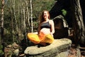 Pregnant woman sitting on stone in easy yoga pose