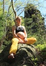 Pregnant woman sitting on stone in half butterfly yoga pose