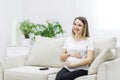 Pregnant woman sitting on white sofa and touching her stomach. Royalty Free Stock Photo
