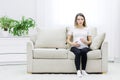 Pregnant woman sitting on white sofa and touching her stomach. Royalty Free Stock Photo