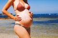 Pregnant woman skin care moisturizer cream on belly on beach at Royalty Free Stock Photo