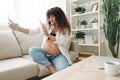 Pregnant woman smile blogger cream for pregnant women stretch marks body during pregnancy filming herself on phone Royalty Free Stock Photo