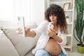 Pregnant woman smile blogger cream for pregnant women stretch marks body during pregnancy filming herself on phone Royalty Free Stock Photo