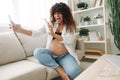 Pregnant woman smile blogger cream for pregnant women stretch marks body during pregnancy filming herself on phone Royalty Free Stock Photo