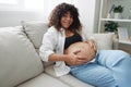 Pregnant woman smile and happiness lies on the couch freedom and strokes her belly with a baby in the last month of Royalty Free Stock Photo