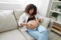 Pregnant woman smile and happiness lies on the couch freedom and strokes her belly with a baby in the last month of Royalty Free Stock Photo