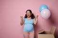 Pregnant woman smiles and shows two fingers at camera, feeling positive emotions expecting twins. Gender reveal party. Royalty Free Stock Photo