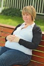 Pregnant woman is smiling on the bench