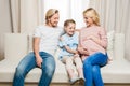 Pregnant woman with smiling husband and daughter sitting on sofa at home Royalty Free Stock Photo